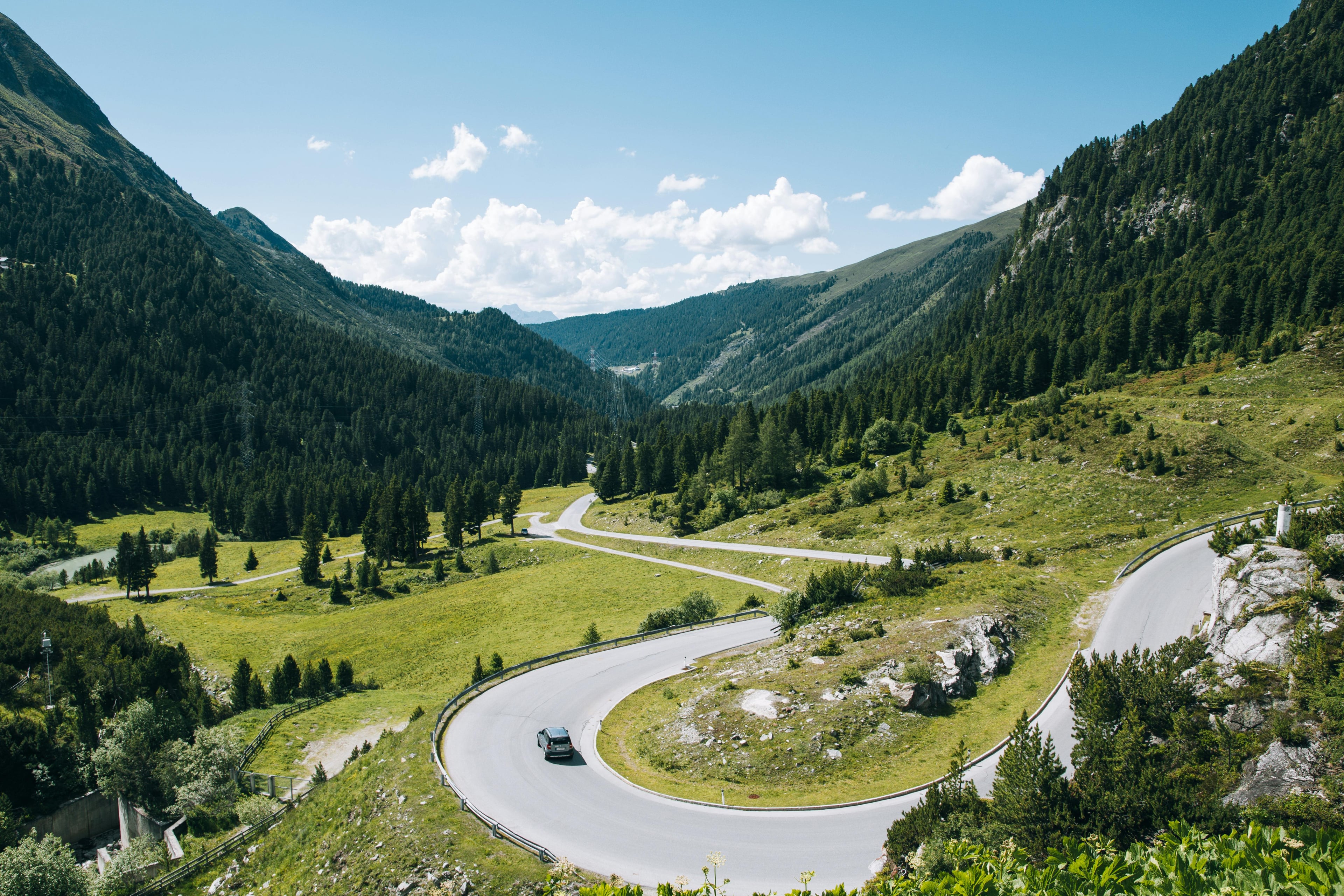 A captivating scenic view of a winding road through the lush green mountains and valleys of Tyrol, Austria.