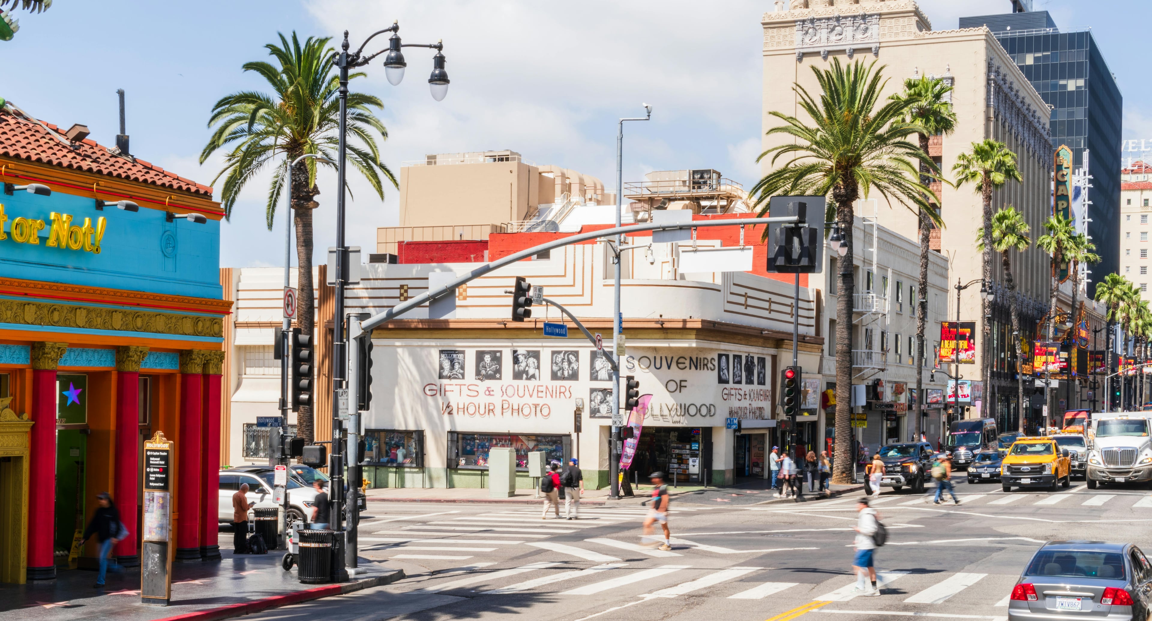 Busy street scene on Hollywood Boulevard with souvenir shops under palm trees, Los Angeles.