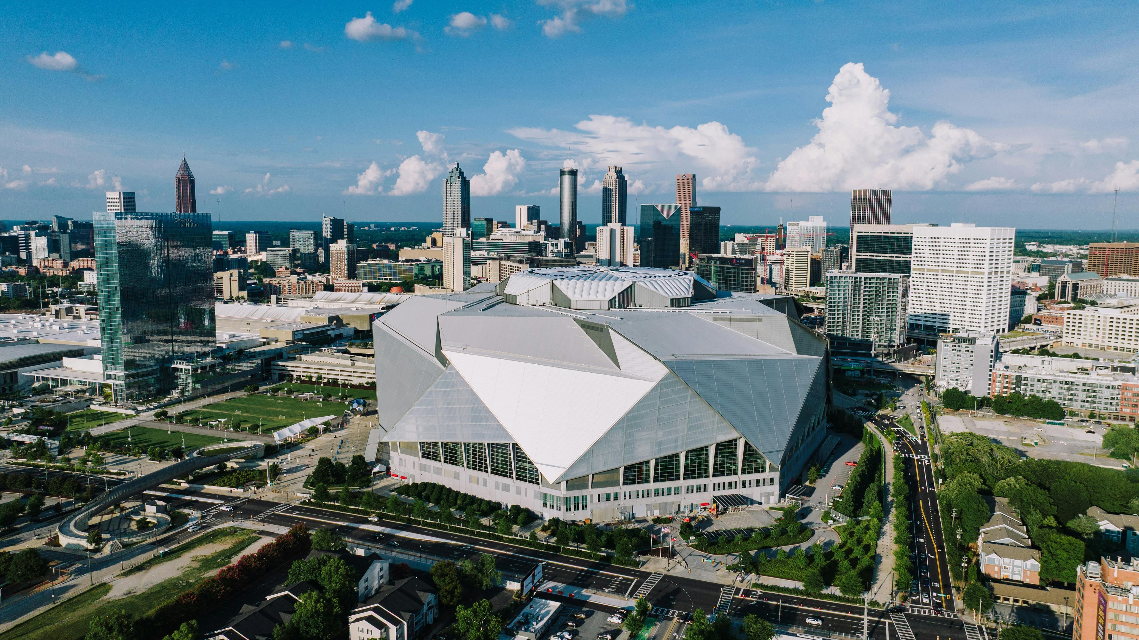 Aerial perspective of Mercedes-Benz Stadium amid the Atlanta skyline under a clear sky.