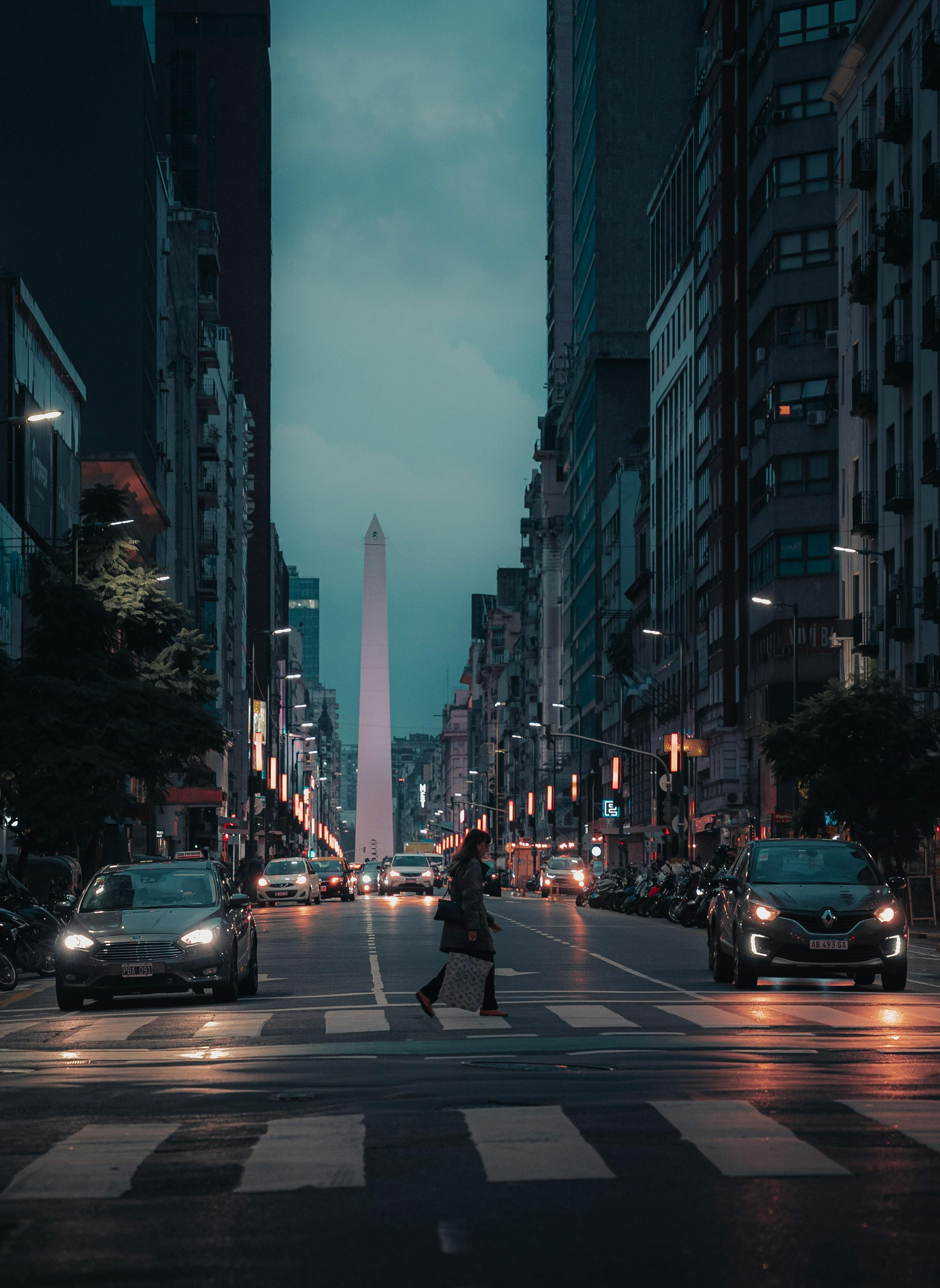 Dramatic night view of Buenos Aires city street, showcasing the iconic Obelisk illuminated amid urban architecture.