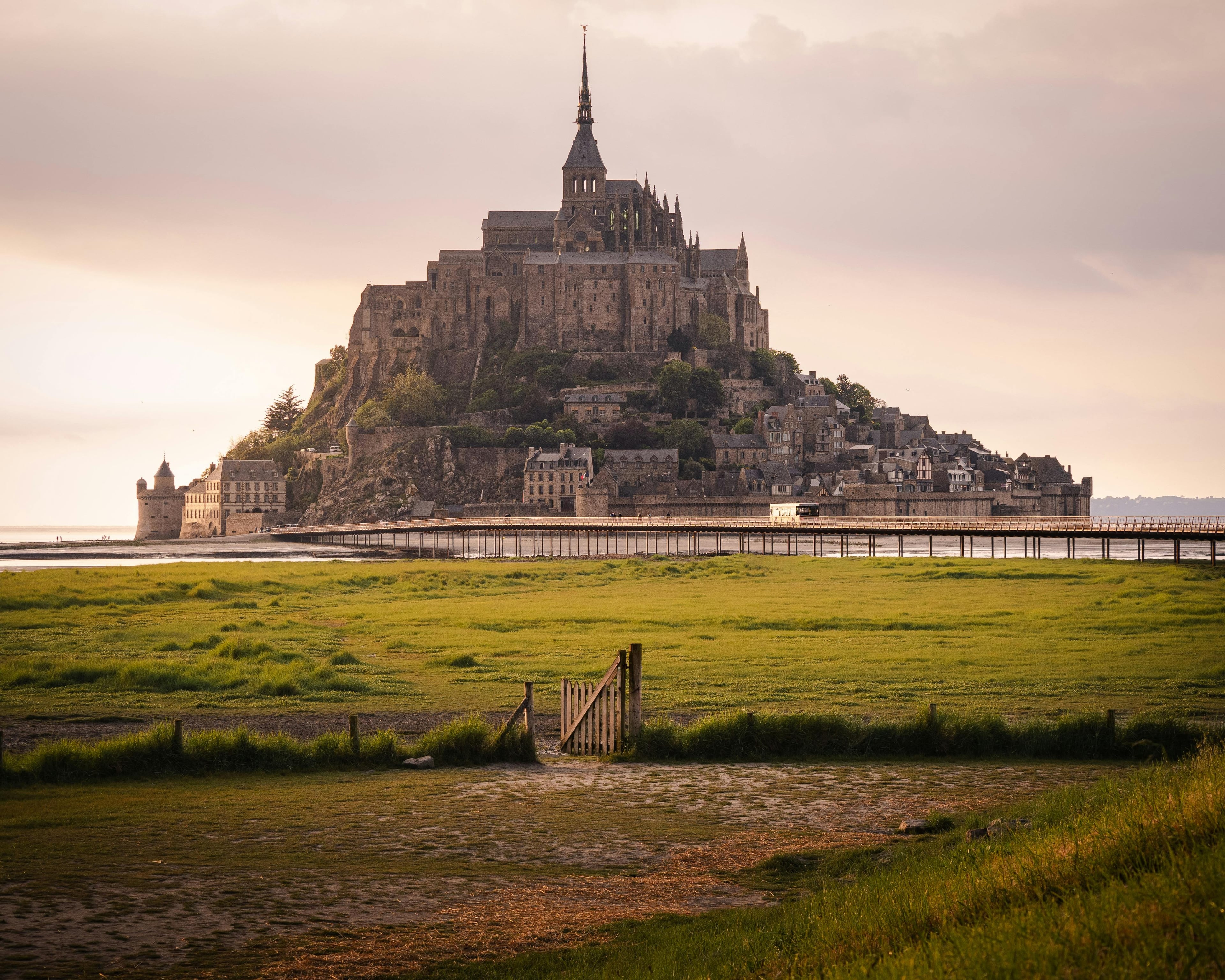 Experience the enchanting view of Mont Saint-Michel, a landmark in France, surrounded by tidal waters at sunset.
