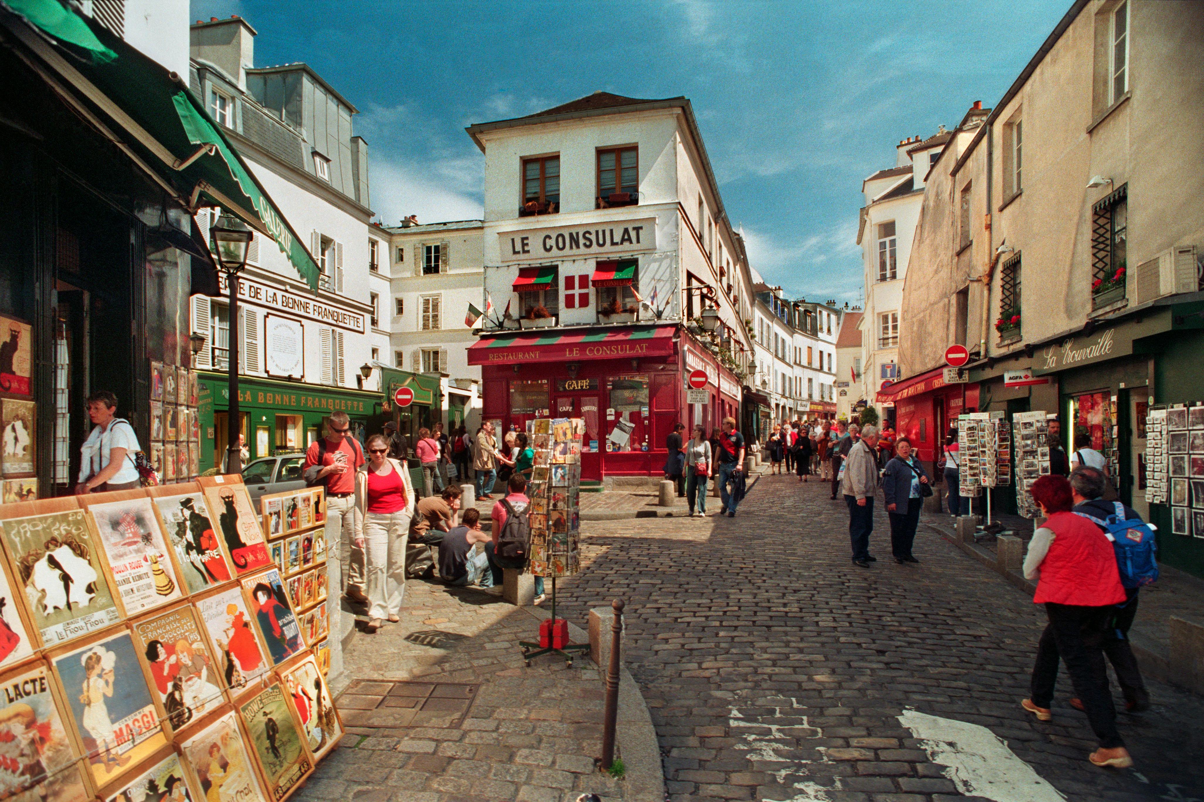 Charming view of Montmartre's cobblestone market street bustling with people on a sunny day.
