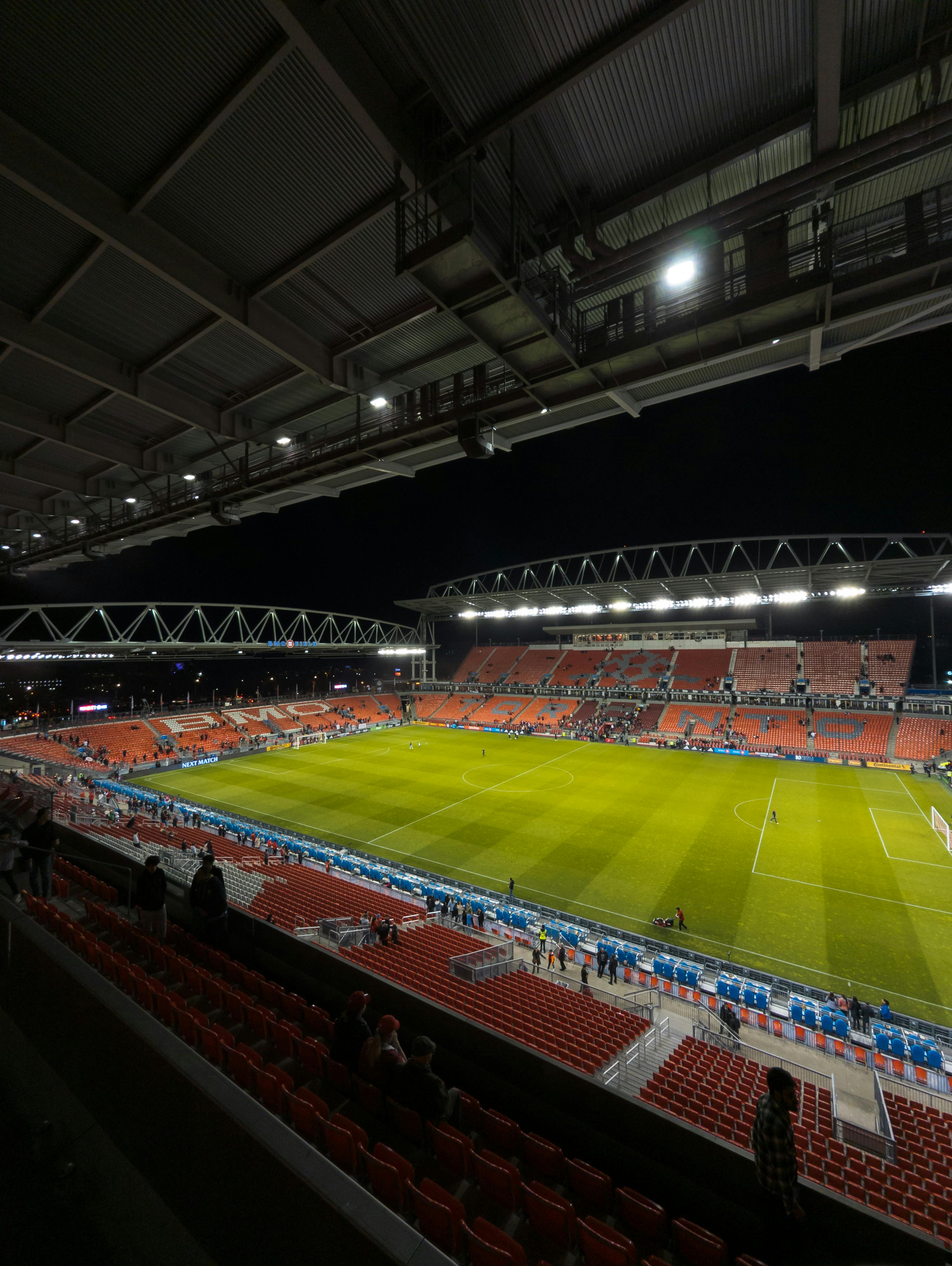 Illuminated BMO Field in Toronto captured at night, showcasing the grandstands and football pitch.
