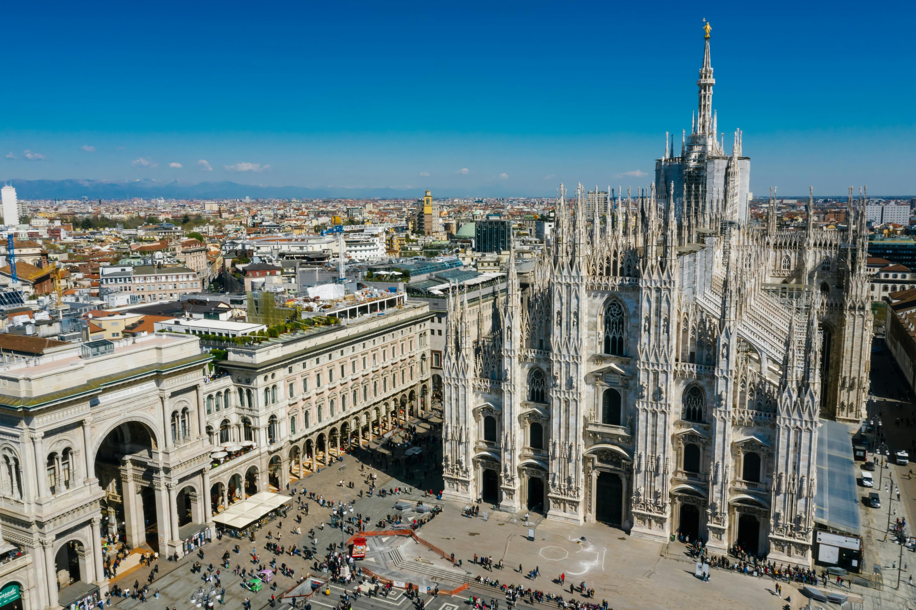 Stunning aerial shot of Milan Cathedral in Italy with bustling cityscape under a clear blue sky.