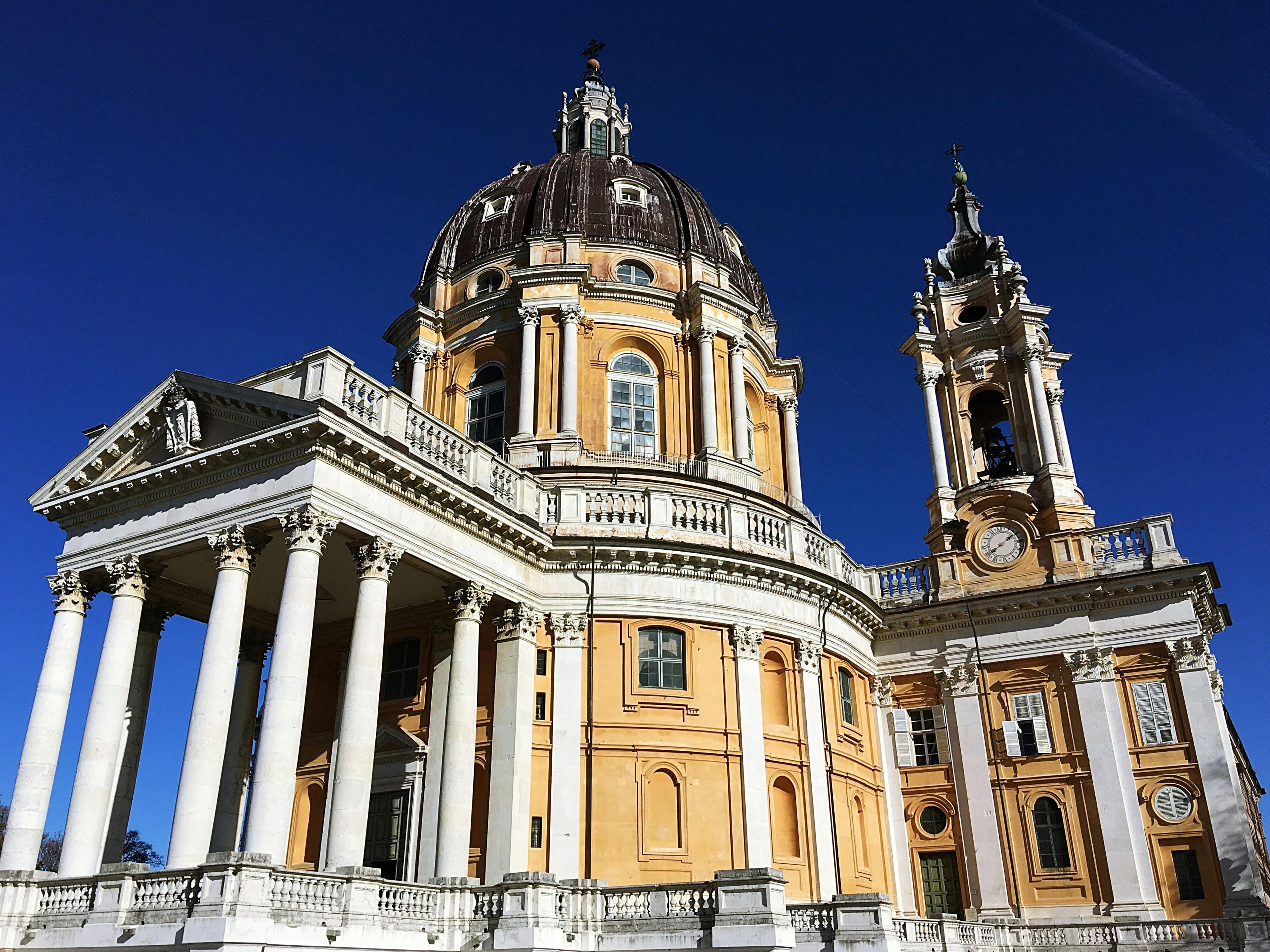 Majestic view of the Basilica of Superga in Torino, showcasing its magnificent baroque architecture under a clear blue sky.